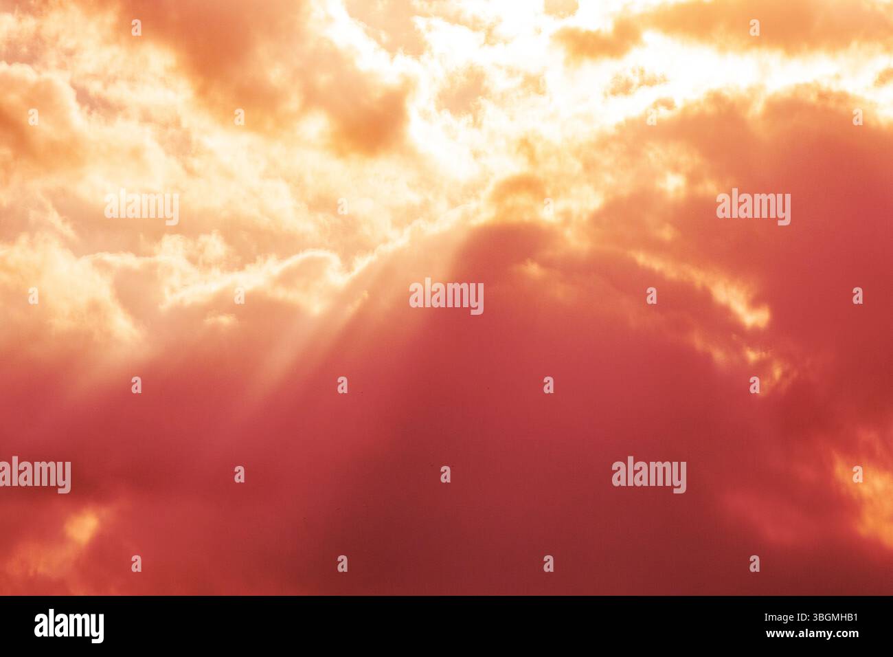 Rosa Wolken bei Sonnenuntergang mit Sonnenstrahlen, stimmungsvoller Himmel mit warmem Licht, rosa Himmel Stockfoto