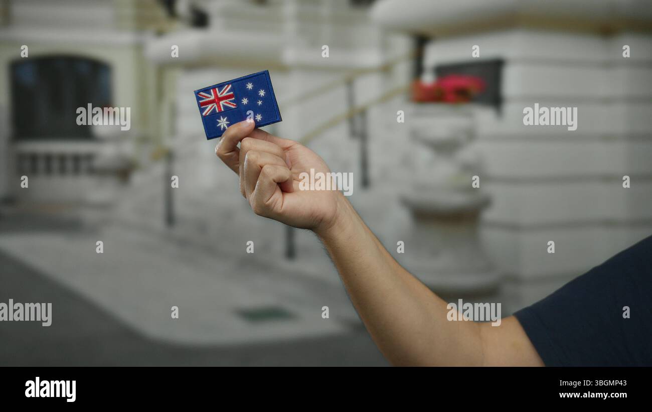 Mann mit Stickerei auf australischer Flagge im Freien auf einer Stadtstraße, die Nationalstolz und kulturelles Erbe zeigt. Stockfoto