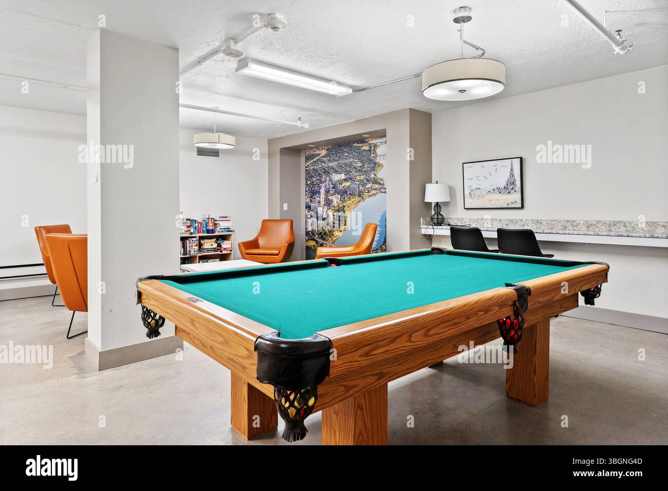 Grüner Billardtisch in einem Raum mit weißer Wand. Das Zimmer ist mit ein paar Stühlen und einer Couch ausgestattet Stockfoto