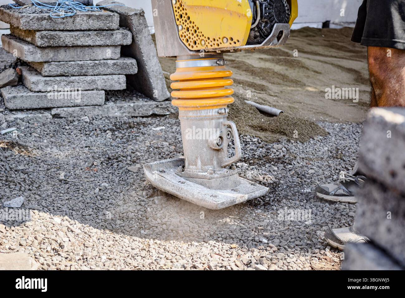 Worker ist die Verdichtung von Kies mit Vibration plate compactor Maschine  in eckigen Graben Stockfotografie