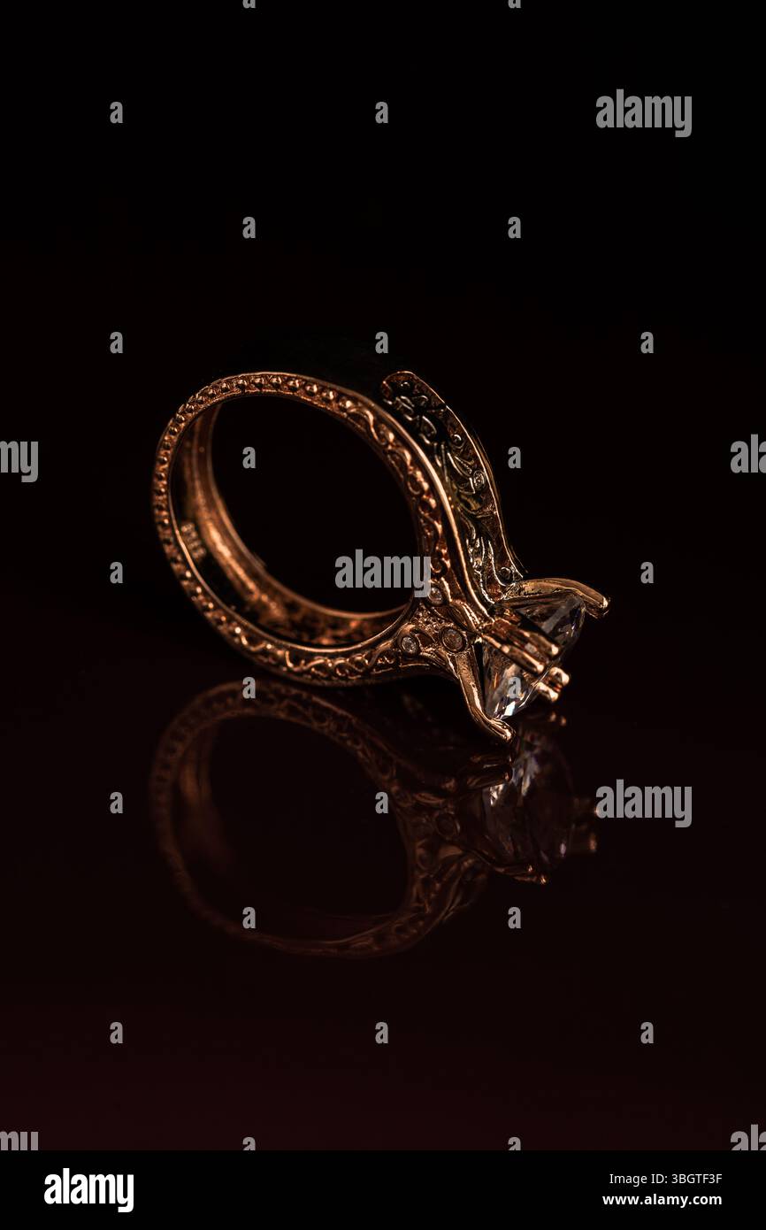 Luxuriöser Schmuck in Nahaufnahme mit goldenem Ring mit Diamanten im scharfen Fokus und stimmungsvollen Schatten – romantisch, elegant, symbolisch und modern. Stockfoto