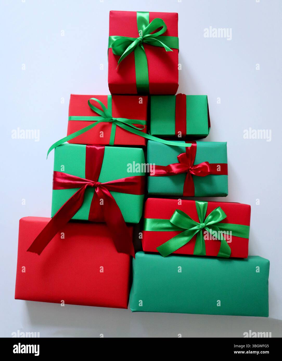 Geschenkset in einer dreieckigen Pyramide. Boxen in verschiedenen Größen. Rot, grün. Gebunden mit Bändern mit Schleifen. Rote Boxen haben grüne Bänder, g Stockfoto