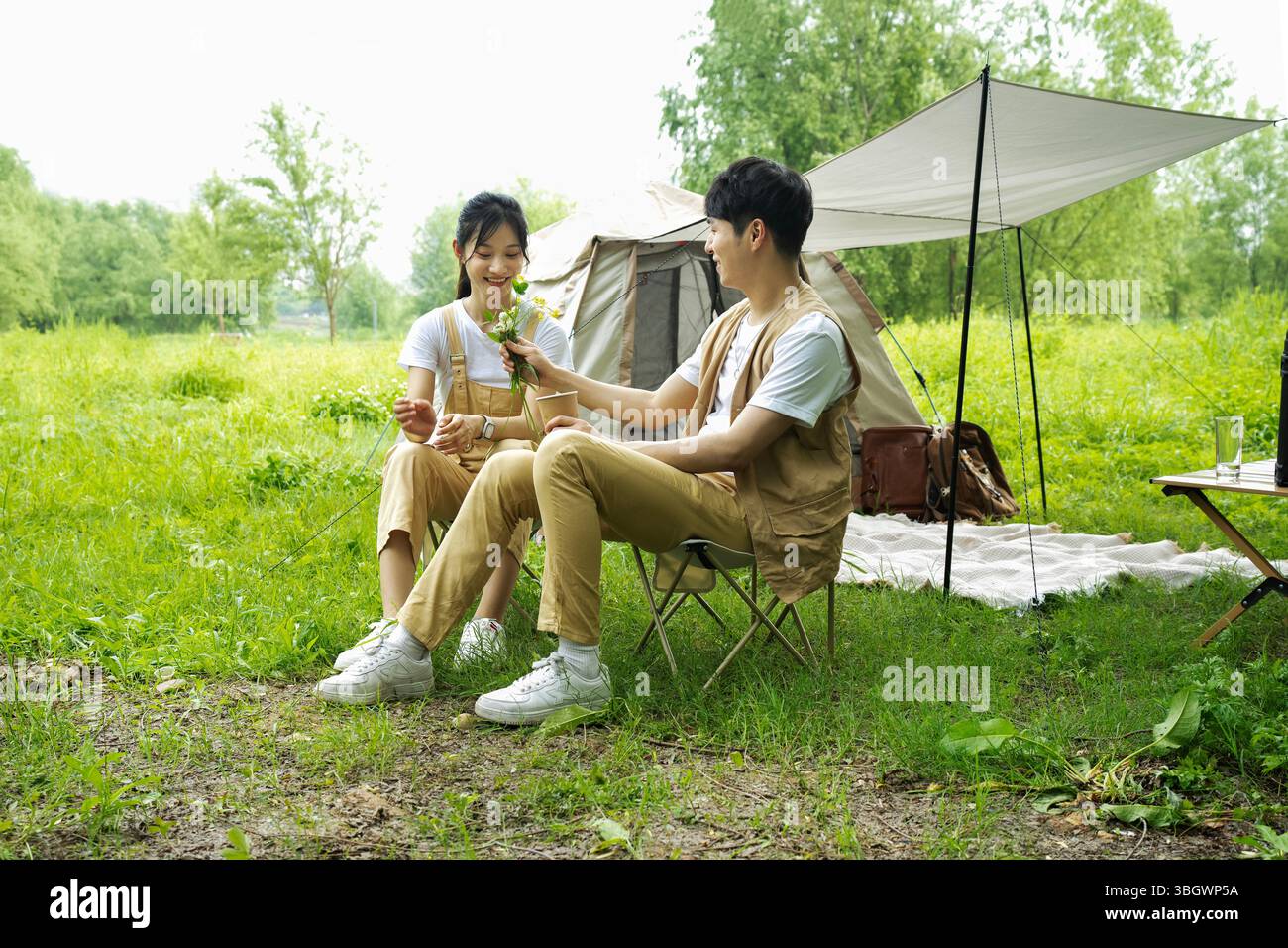 Junge Paare, die nebeneinander sitzen und Wildblumen teilen Stockfoto