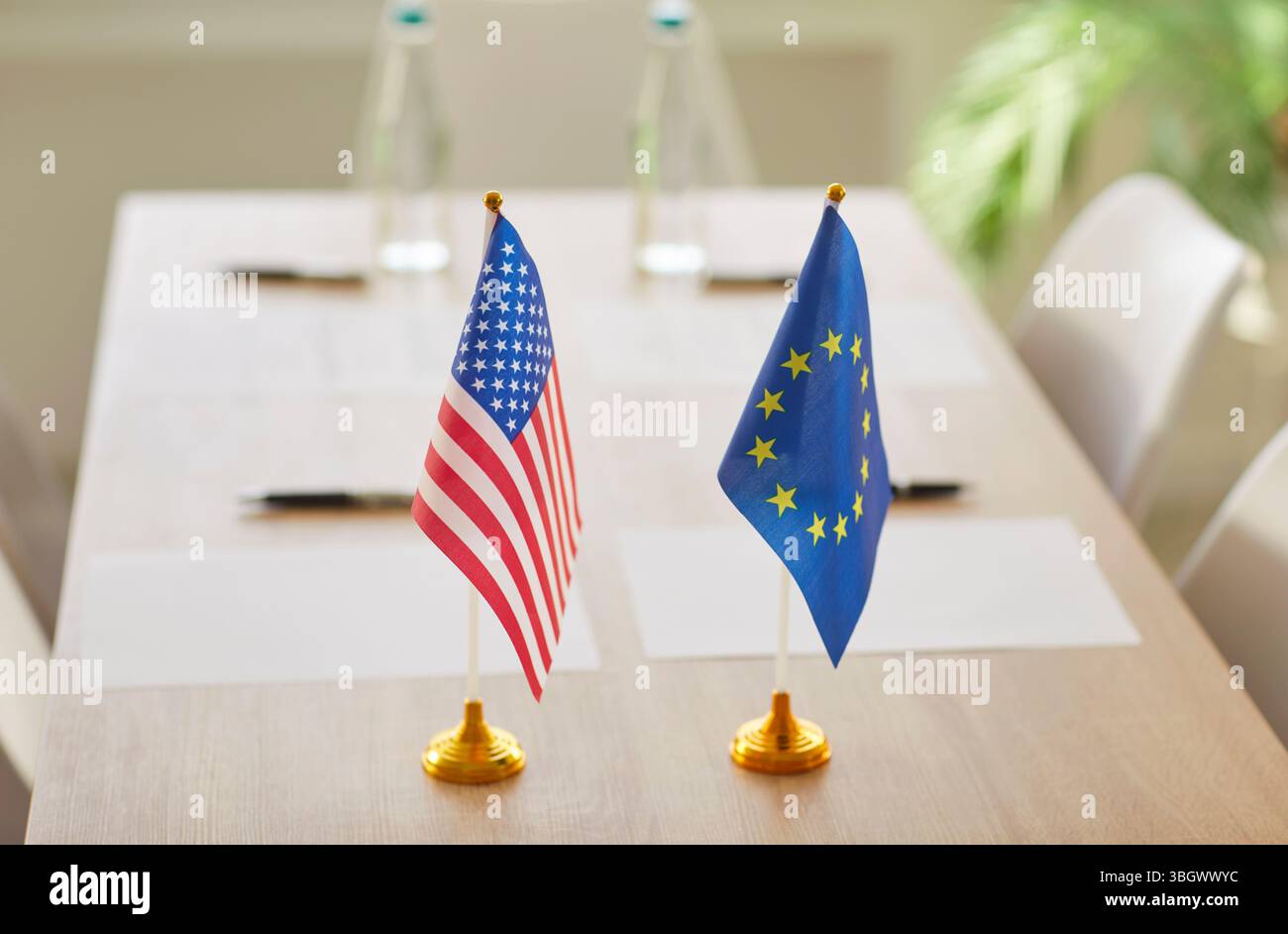Flaggen der Vereinigten Staaten und der Europäischen Union stehen bei internationalen Verhandlungen an einem Tisch Stockfoto