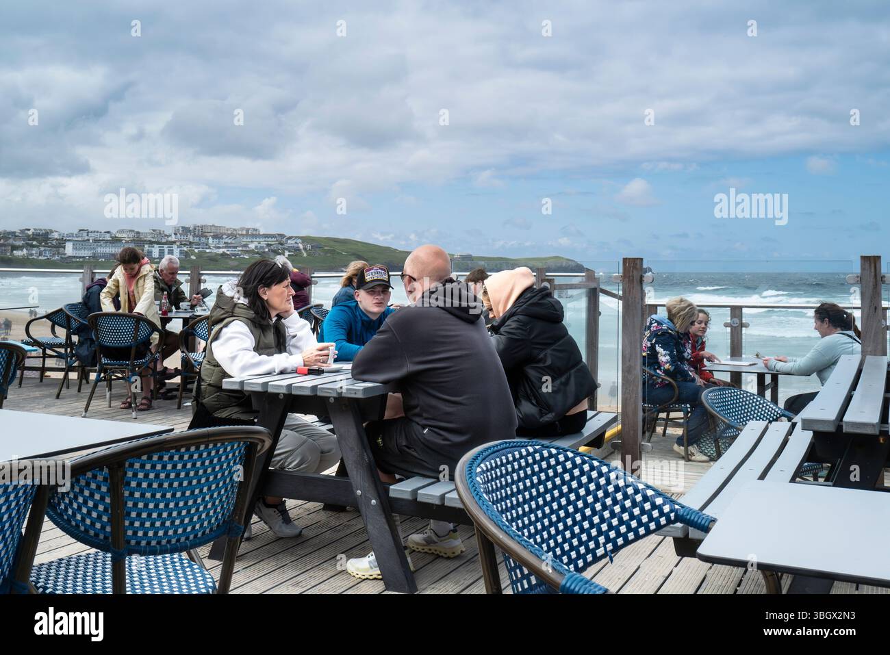 Urlauber sitzen an Picknicktischen auf dem Terrassenbereich der Fistral Beach Bar in Newquay in Cornwall, Großbritannien. Stockfoto