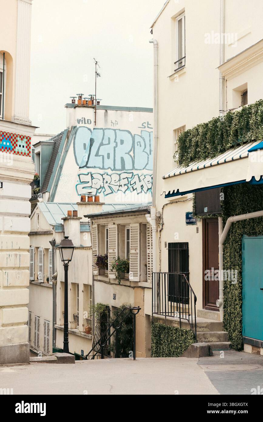 Eine charakteristische Pariser Gassenszene mit traditionellen Gebäuden mit Fensterläden und einer alten Straßenlaterne, die mit prominenten Graffiti A gegenübergestellt wird Stockfoto