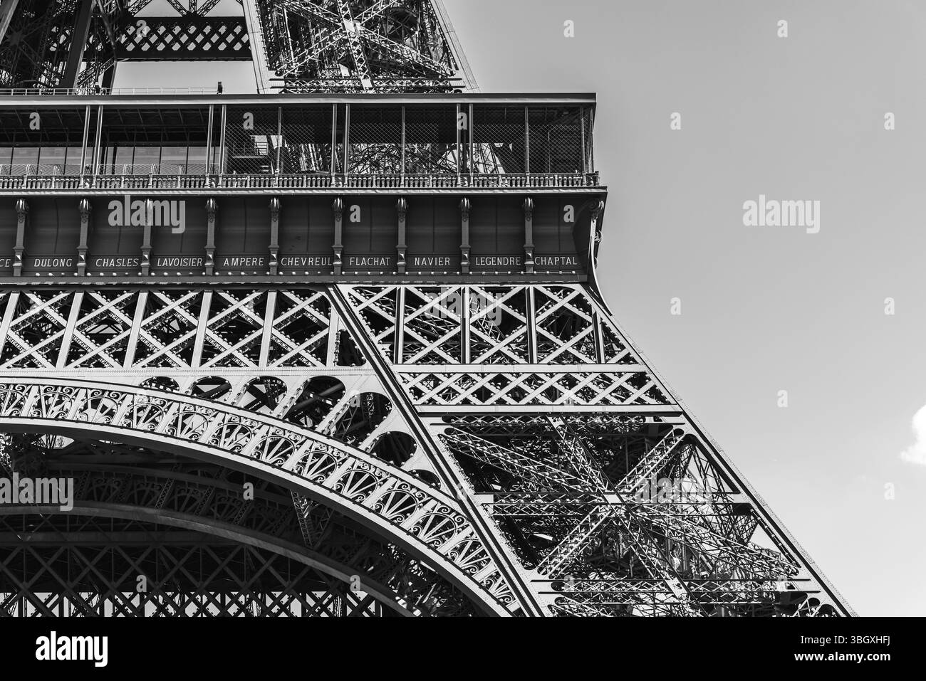 Eine Schwarzweiß-Nahaufnahme, die das komplizierte Eisen und die architektonischen Details der ersten Plattform des Eiffelturms mit Gravur hervorhebt Stockfoto