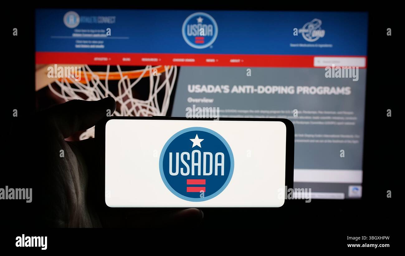 Stuttgart, Deutschland - 03.12.2025: Person mit Mobiltelefon mit Logo der US-amerikanischen Anti-Doping-Agentur (USADA) auf dem Bildschirm vor der Webseite. Stockfoto