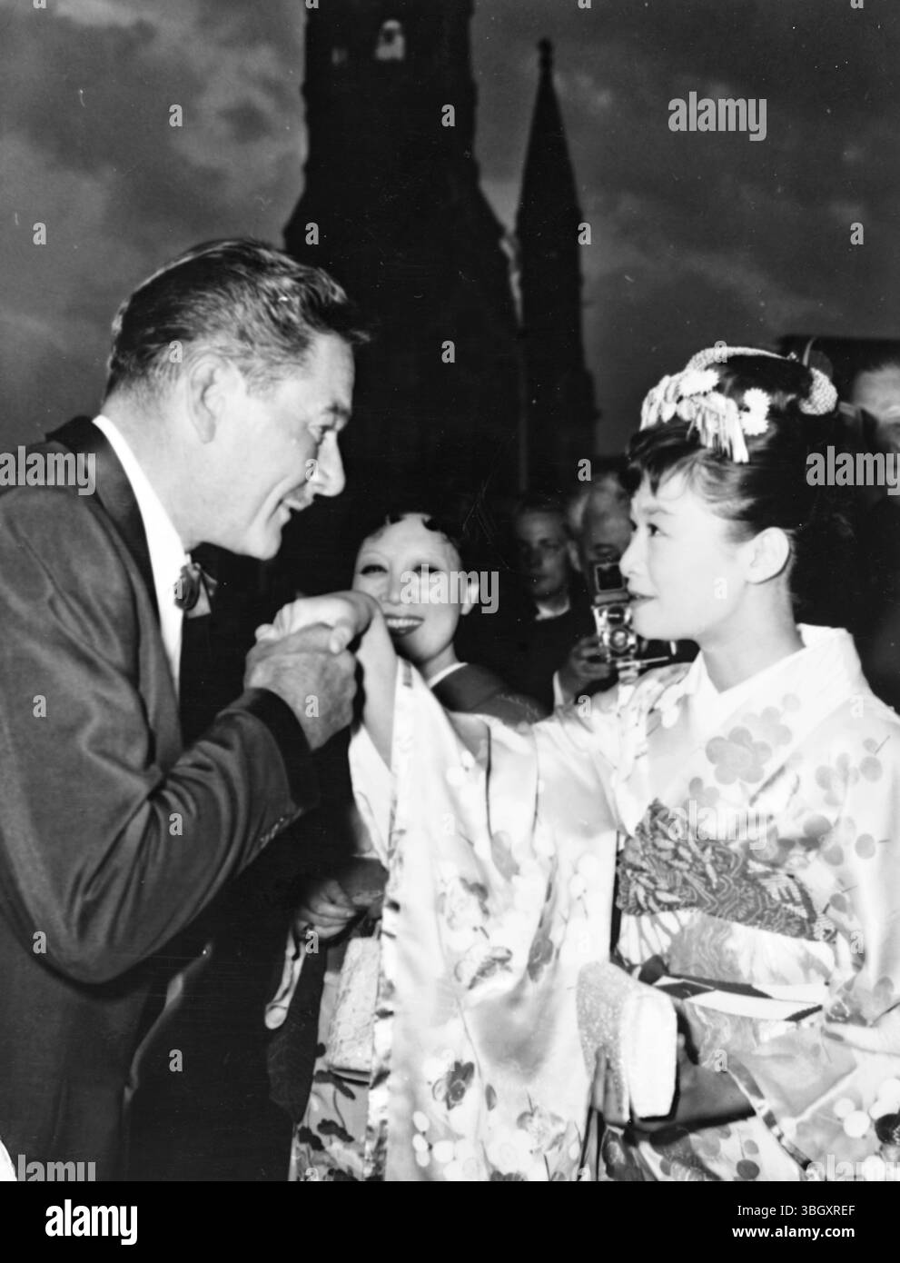 Errol Flynn begrüßt den japanischen Filmstar Izumi Yukimura vor dem Hintergrund der Ruine der West-Berliner Saints Memorial Church. Flynn und Miss Sukimura sind für das 7. Internationale Filmfestival in Berlin. 21. Juni 1957 Stockfoto
