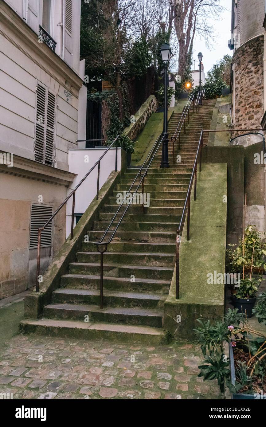 Eine alte, verwitterte Steintreppe mit Metallgeländern führt sich in einer engen, ruhigen Gasse nach oben, wahrscheinlich in einem historischen europäischen Viertel. Laternenpfosten i Stockfoto