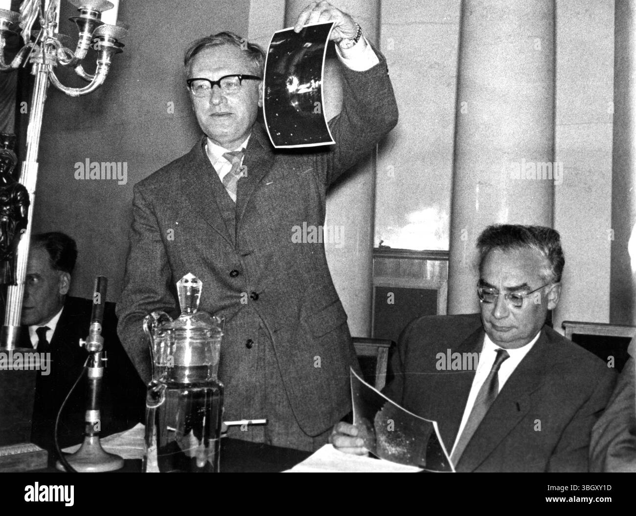 Professor Alexander Topchiev – sowjetischer Chemiker/Wissenschaftler mit einem Foto der Rakete „Lunik“ und Boris Koukarkin Astronaut (rechts sitzend) nimmt sich das Foto genauer an. [Bildunterschrift auf Französisch] 15. September 1959 Stockfoto