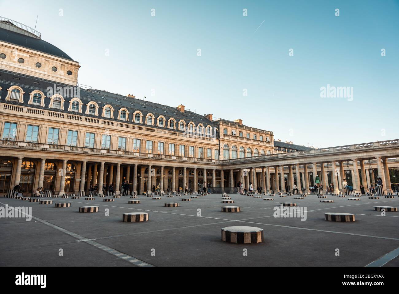 Ein großer Blick auf den historischen Innenhof des Pariser Palastes mit umfangreichen Kolonnaden und einer modernen Kunstinstallation aus schwarz-weiß gestreiften Säulen. N Stockfoto