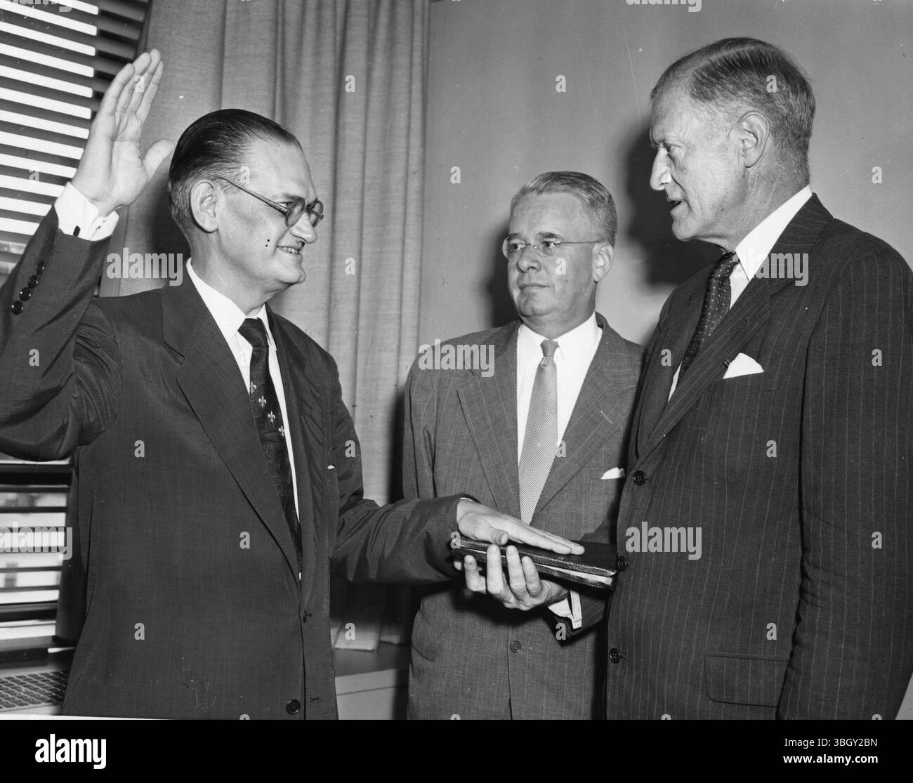 James W. Riddleberger wird als neuer Botschafter der Vereinigten Staaten in Jugoslawien vereidigt. John Simmons (rechts), Leiter des State Department of Protocol, legt den Eid ab, als der stellvertretende Untersekretär von State H. Freeman Matthews zusieht. 14. August 1953 Stockfoto