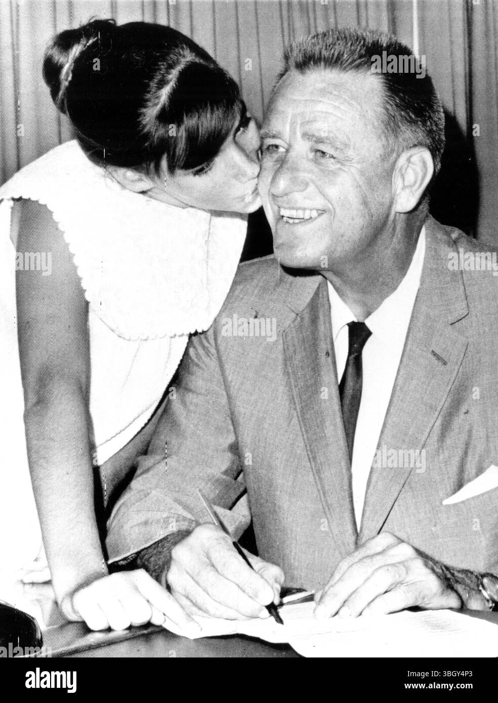 Elliott Roosevelt, Sohn des verstorbenen Präsidenten Franklin D Roosevelt, erhält einen großen Kuss von seiner Tochter Gretchen auf die Wange, nachdem er Formulare unterzeichnet hat, in denen er als Bürgermeister kandidieren wird. 20. April 1965 Stockfoto