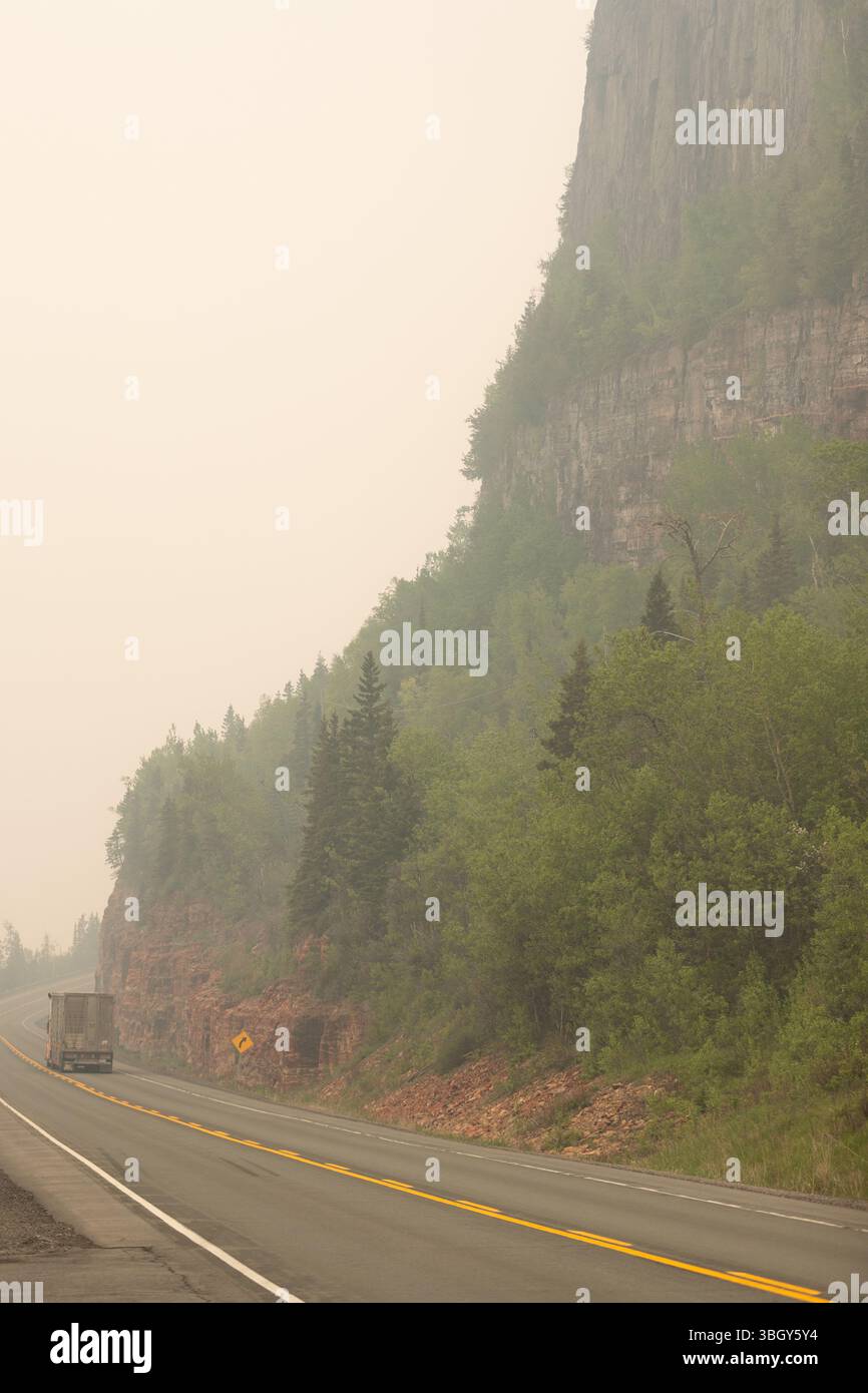 Kama, Kanada - 3. Juni 2025. Rauch von Waldbränden in Manitoba und Nord-Ontario umhüllt die Region, während Fahrzeuge entlang der Trans Canada Highwa fahren Stockfoto
