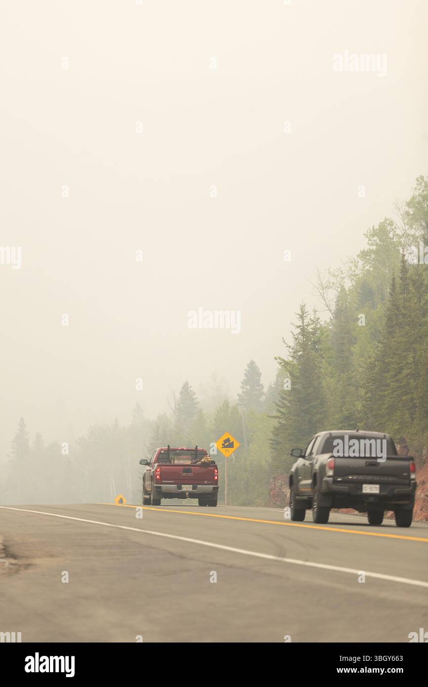Kama, Kanada - 3. Juni 2025. Rauch von Waldbränden in Manitoba und Nord-Ontario umhüllt die Region, während Fahrzeuge entlang der Trans Canada Highwa fahren Stockfoto