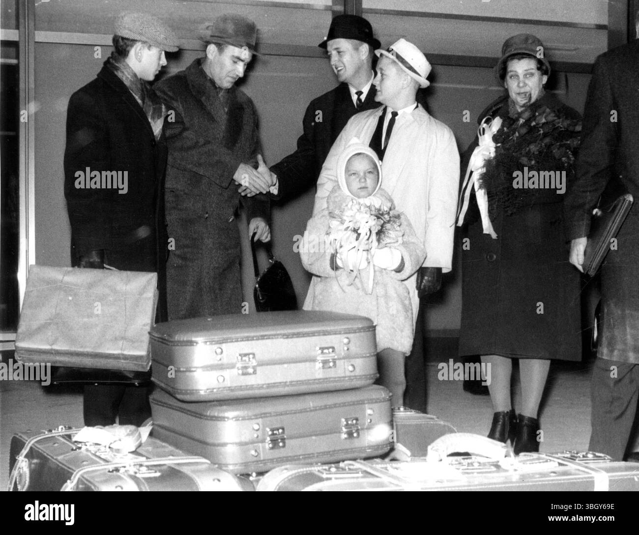 Willkommen in der russischen Familie. Der russische Ingenieur Viktor Pozdnejew, 39 (2. Links), und seine Familie werden von ihrem amerikanischen Gastgeber James C, McKenzie, 34 (mittlerer dunkler Mantel) aus Portsmouth bei der Ankunft am John F Kennedy International Airport am 19. Dezember begrüßt, um weihnachten mit der US-Familie in einer internationalen Wohlwollen-Geste zu verbringen, die von der Portsmouth Junior Chamber of Commerce gesponsert wird. 19. Dezember 1963 Stockfoto