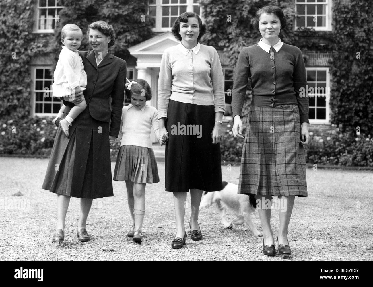 Lady Makins, die in Amerika geborene Ehefrau von Sir Roger Makins, Großbritanniens neuernannter Botschafter in Washington, schlendert mit vier ihrer 6 Kinder durch den Garten eines Hauses. In ihren Armen ist die 18 Monate alte Dwight. Die anderen sind Patricia im Alter von 6 Jahren und die 17-jährigen Zwillinge Mollie und Cynthia. Dahinter läuft der Hund, Ronnie. 5. Oktober 1952 Stockfoto