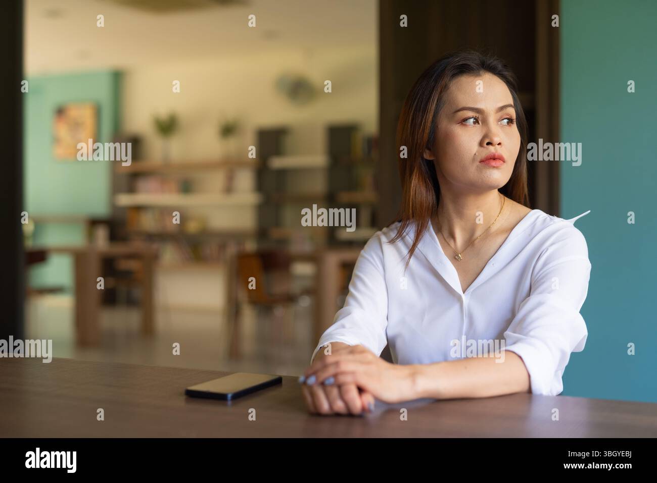 Porträt einer schönen asiatischen Frau, die in der Bibliothek sitzt Stockfoto