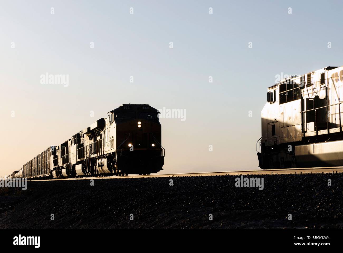 Zwei Silhouettenzüge treffen bei Sonnenuntergang auf Stockfoto