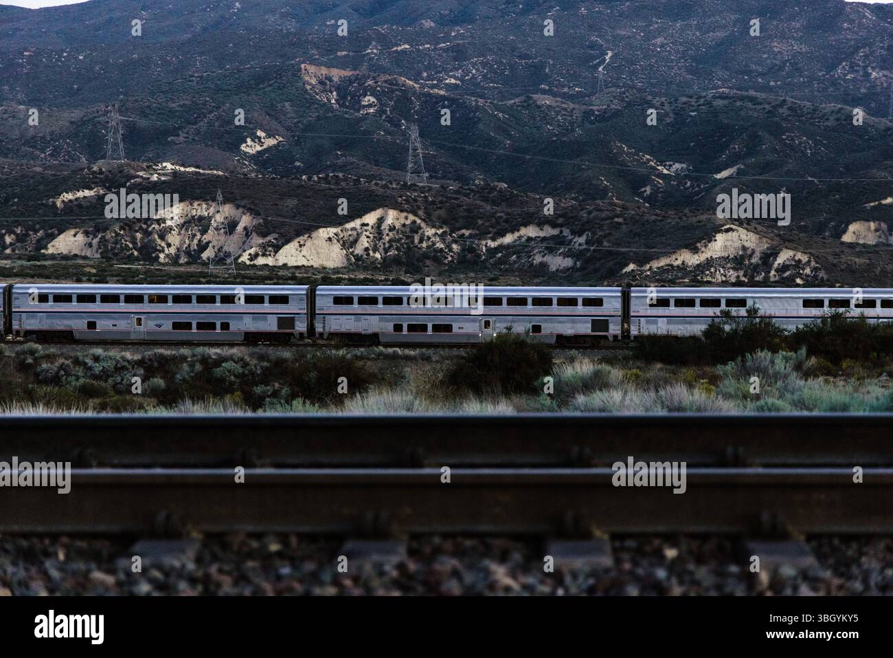 Amtrak-Personenkraftwagen, die Eisenbahngleise im Vordergrund passieren Stockfoto