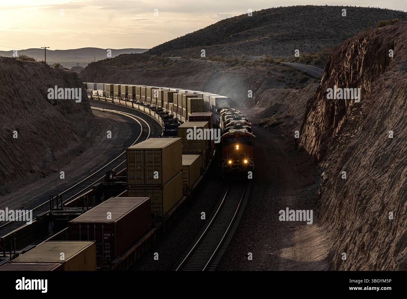 Drei Züge fahren im felsigen Tal bei Sonnenuntergang Stockfoto