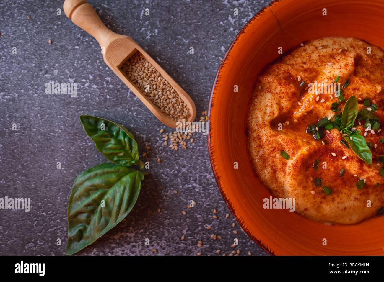 Hummus dekoriert mit Kräutern und Sesamsamen in einer Orangenschale Stockfoto