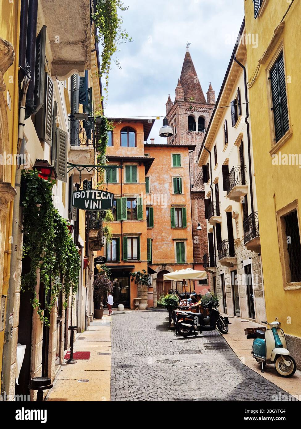 Bezaubernde europäische Straße mit farbenfrohen Gebäuden und Vintage-Roller. Verona, Italien Stockfoto
