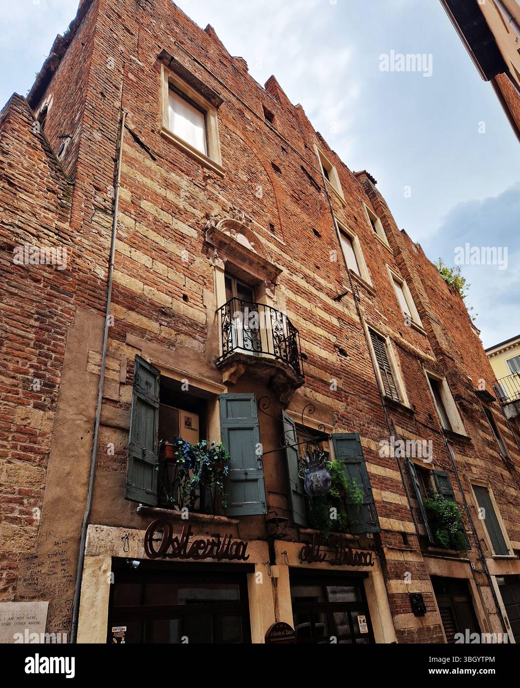 Charmantes historisches Gebäude mit rustikaler Fassade und verschließbaren Balkonen. Verona, Italien Stockfoto