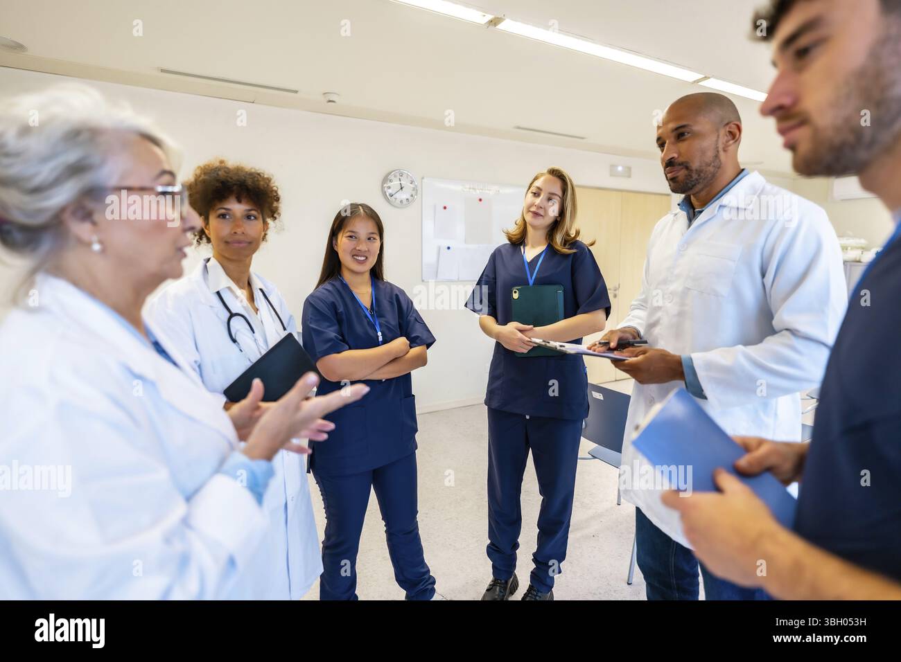 Verschiedene medizinische Fachkräfte arbeiten zusammen, tauschen Fachwissen aus und prüfen Patientendaten während einer produktiven Besprechung im Krankenhaus Stockfoto