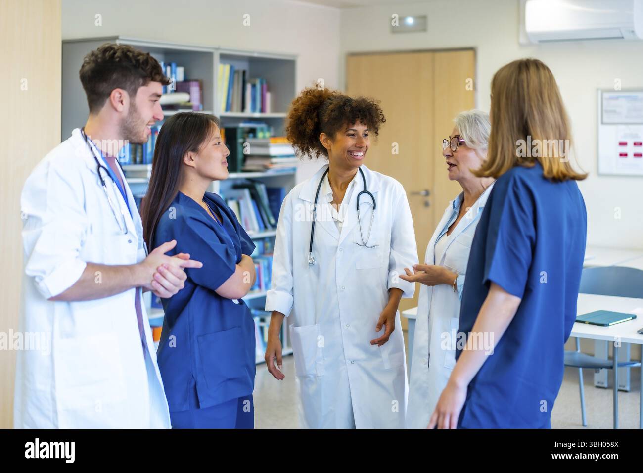 Vielfältige medizinische Fachkräfte arbeiten zusammen, tauschen Fachwissen aus und entwickeln Strategien für eine optimale Patientenversorgung in einer Krankenhausumgebung Stockfoto