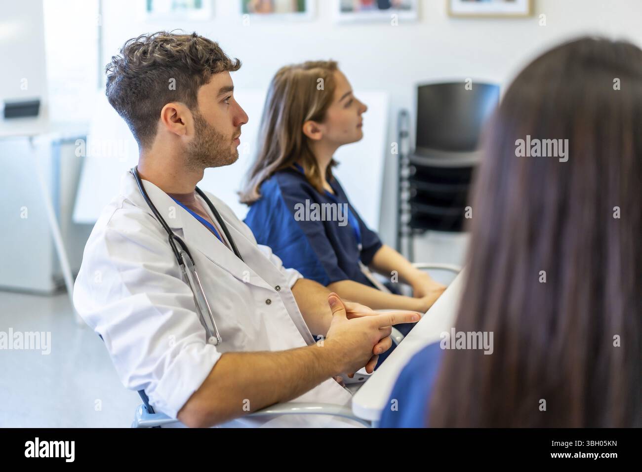 Medizinische Fachkräfte, die an einer Konferenz in einem Besprechungsraum des Krankenhauses teilnehmen, einer Präsentation zuhören und neue Fähigkeiten erlernen Stockfoto