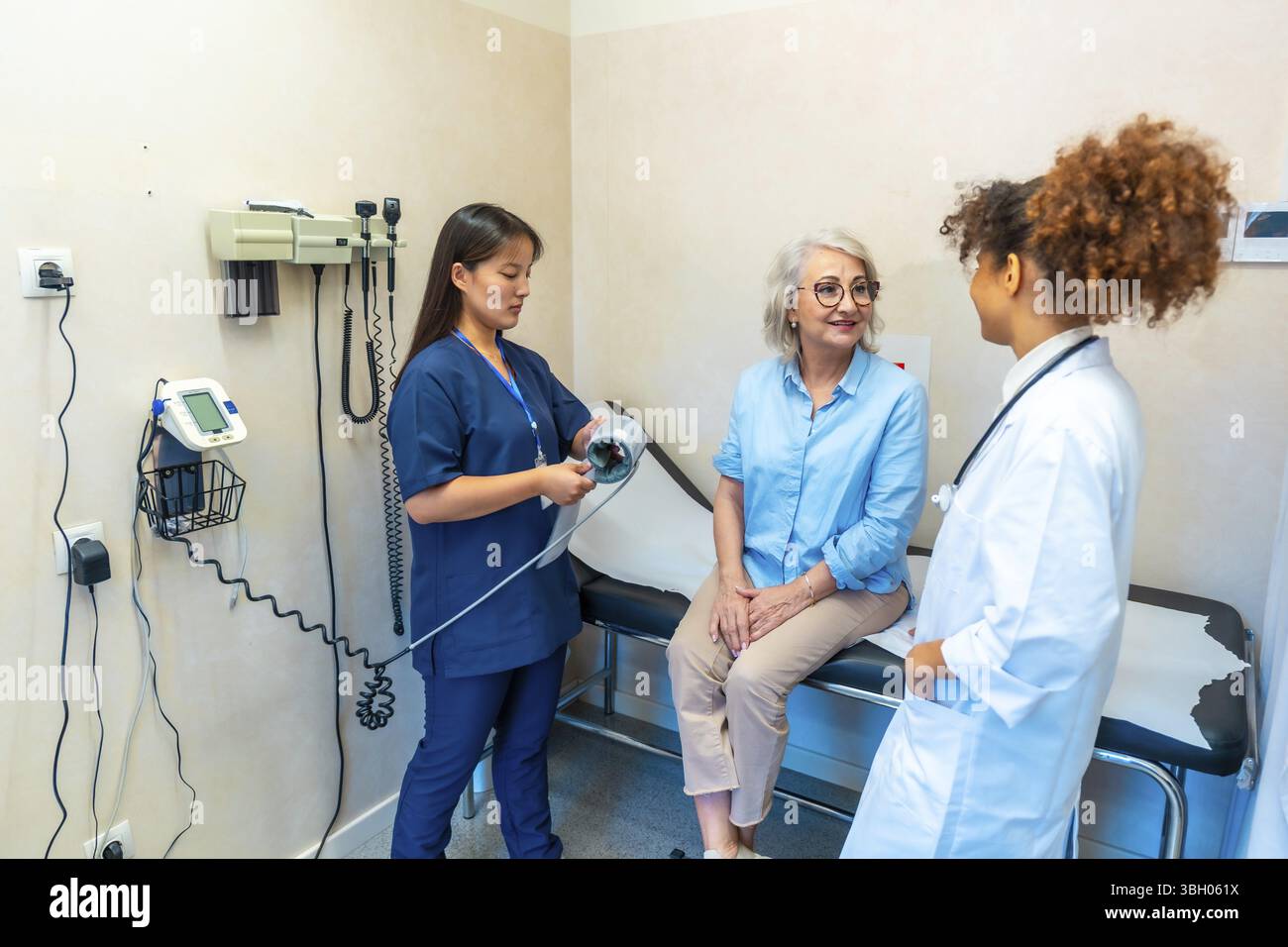 Medizinische Fachkräfte, die eine ältere Frau während einer medizinischen Untersuchung besuchen und sich auf die Messung ihres Blutdrucks vorbereiten Stockfoto