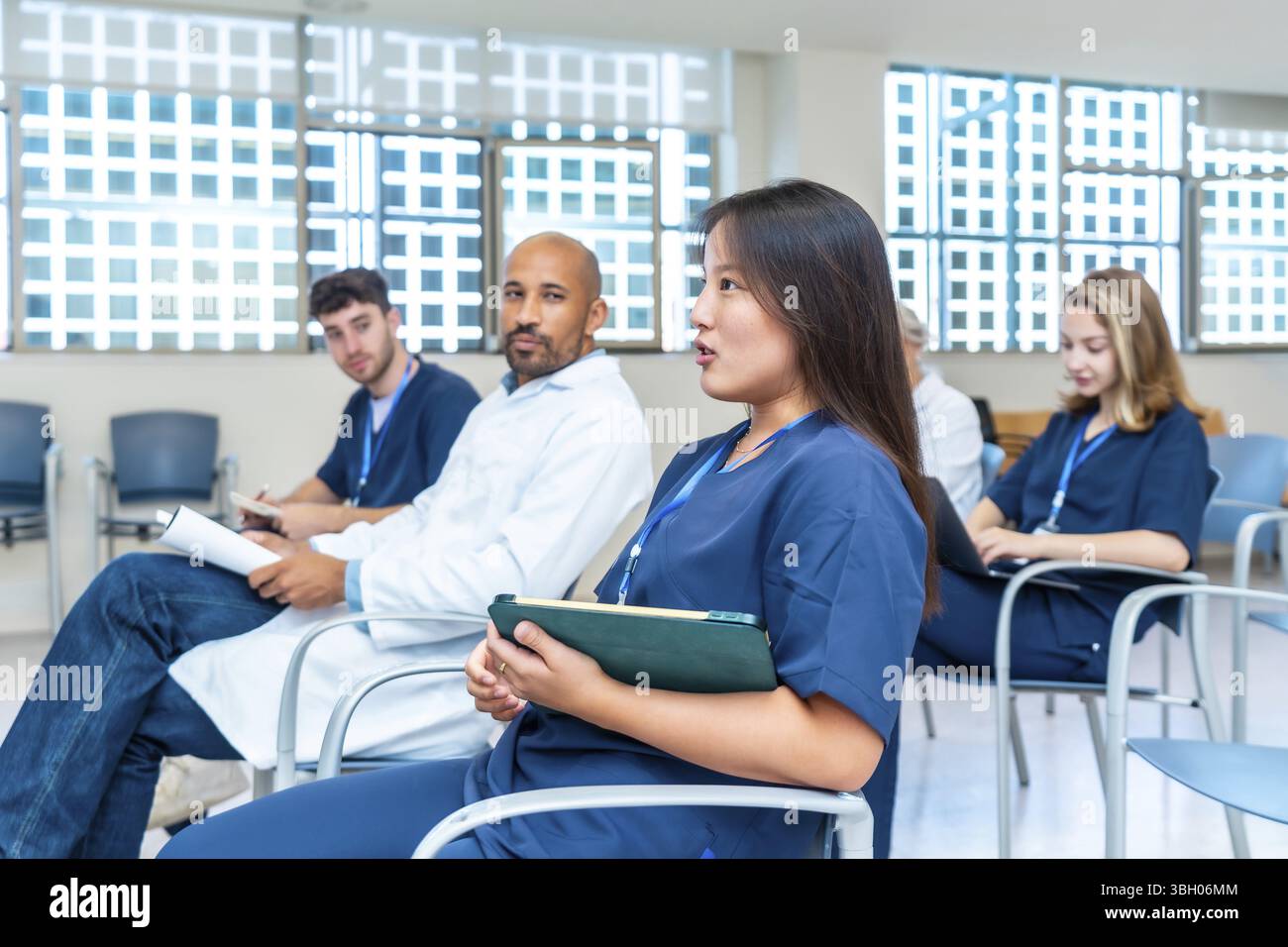 Vielfältige Gruppe von medizinischen Fachkräften, die an einer medizinischen Konferenz teilnehmen, aktiv an Diskussionen teilnehmen und Notizen machen Stockfoto