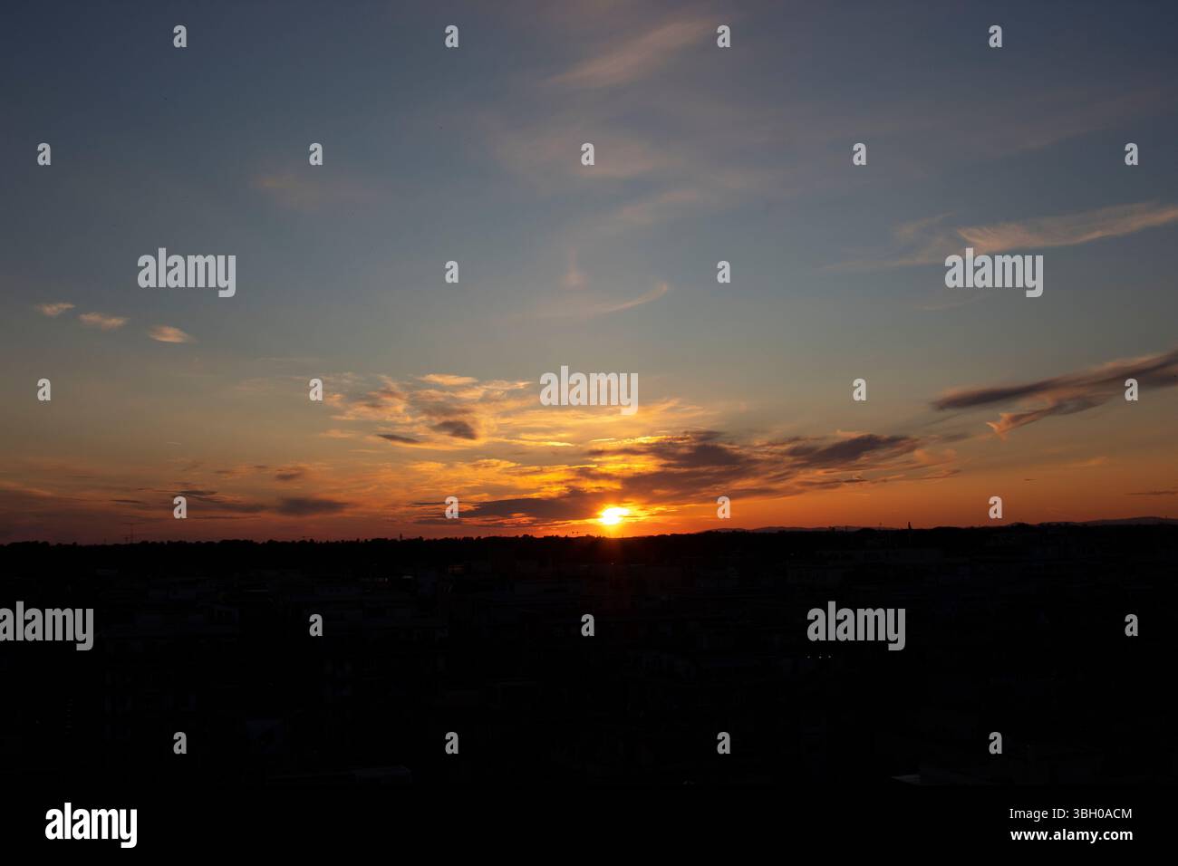 Sonnenuntergangshimmel mit warmen Farben und weichen Wolken über einer natürlichen Landschaft, erfasst während der goldenen Stunde. Stockfoto