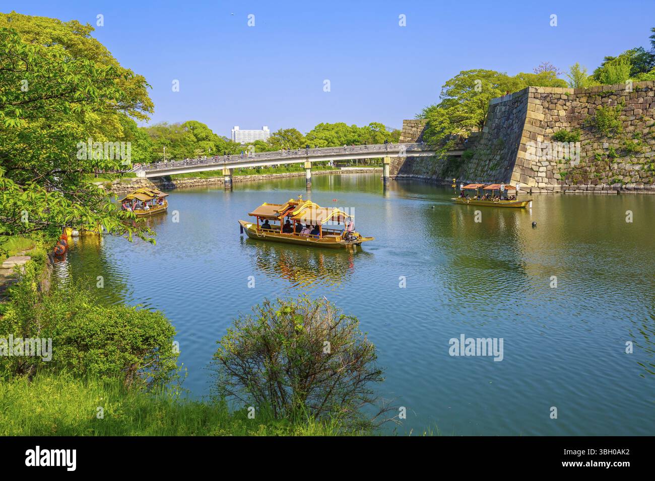 Touristenboote entlang des Burggrabens und der Mauer der Burg Osaka, während sie die beliebte Gokurakubashi-Brücke oder die Gokuraku-Brücke überqueren, die nach Osaka Castle P führt Stockfoto