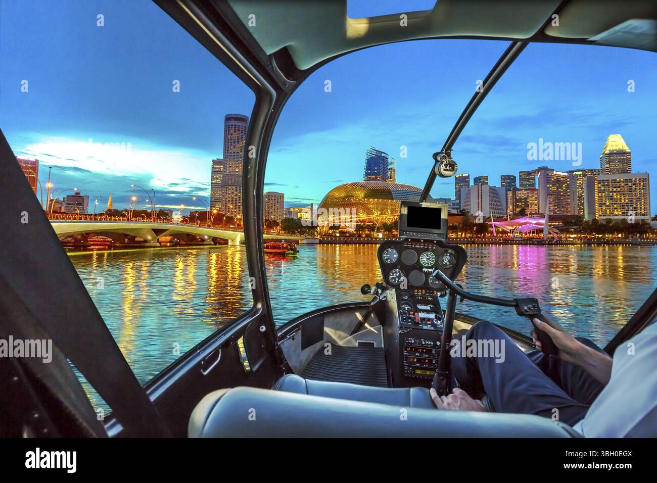Hubschrauber-Cockpit-Innenraum fliegt auf der Skyline von Singapur in der Marina Bay mit Kreuzfahrtschiffen im Hafen zur blauen Stunde. Nachtszene am Wasser in Singa Stockfoto