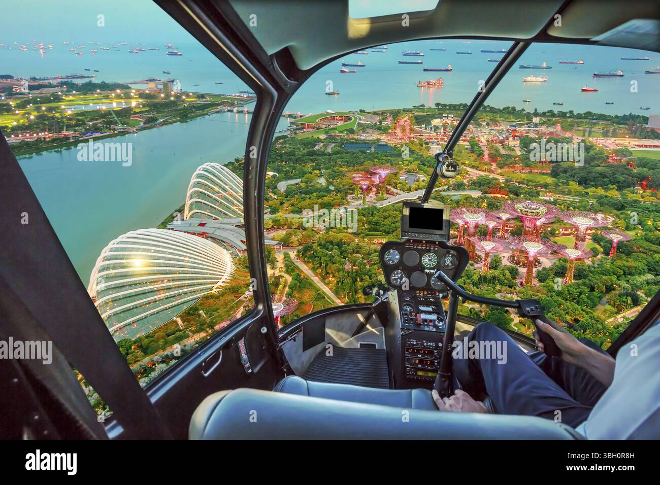 Hubschrauber-Cockpit-Innenraum fliegt in der Bucht von Singapur. Malerischer Flug über Gärten an der Skyline der Bucht. Nächtliche urbane Luftszene Stockfoto Hubschrauber-Cockpit-Innenraum fliegt in der Bucht von Singapur. Malerischer Flug über Gärten an der Skyline der Bucht. Nächtliche urbane Luftszene Stockfoto