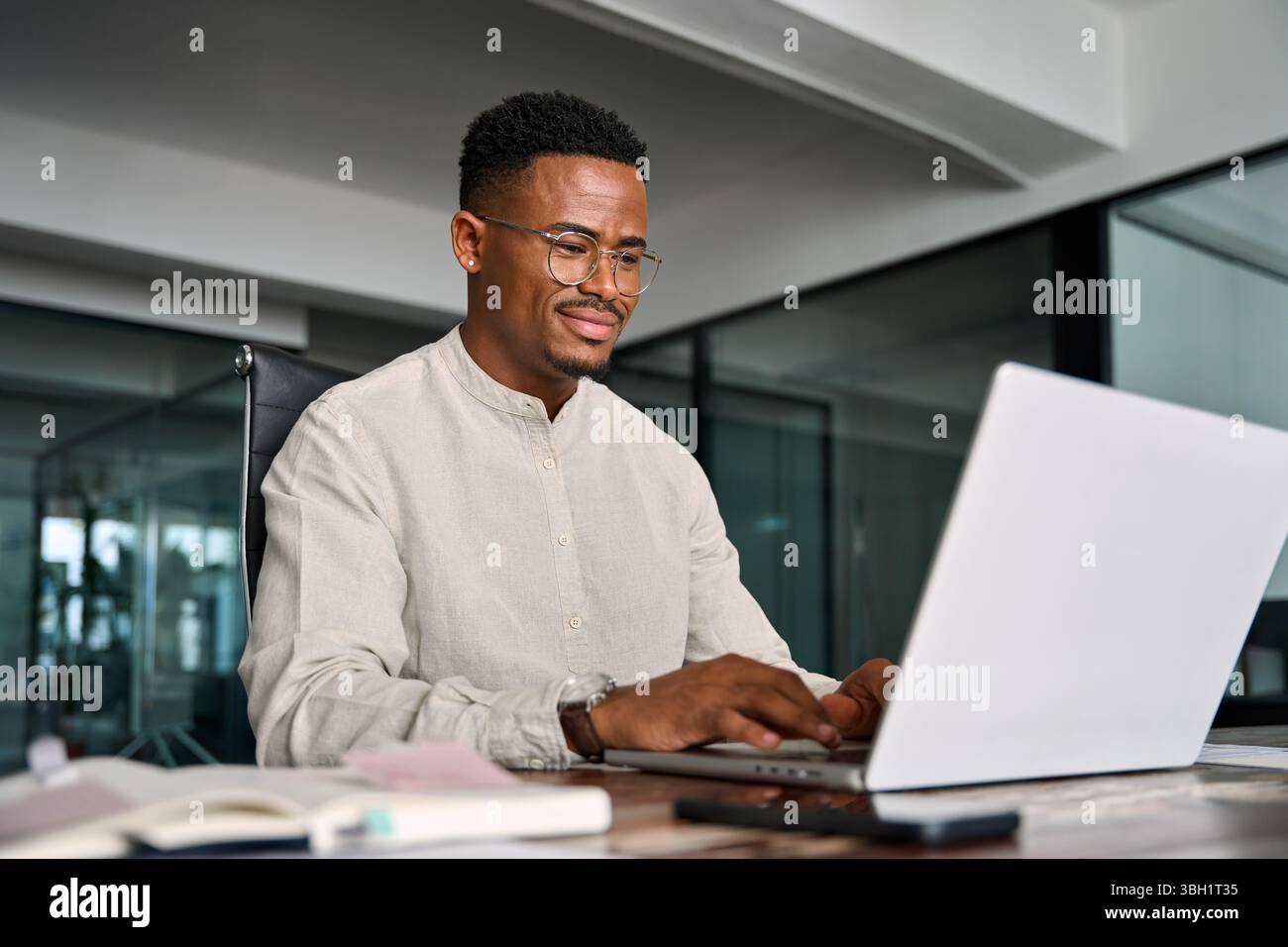 Beschäftigter professioneller afrikanischer Geschäftsmann, der im Büro mit einem Laptop arbeitet. Stockfoto