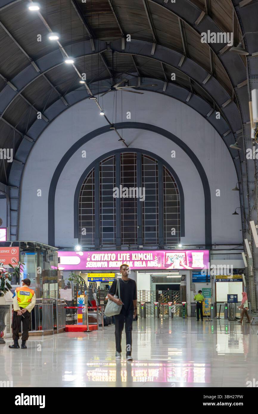 Jakarta, Indonesien - 9. Februar 2025: Bahnhof Jakarta Kota bei Nacht. Der Mann läuft einen langen Flur entlang. Der Flur ist beleuchtet Stockfoto