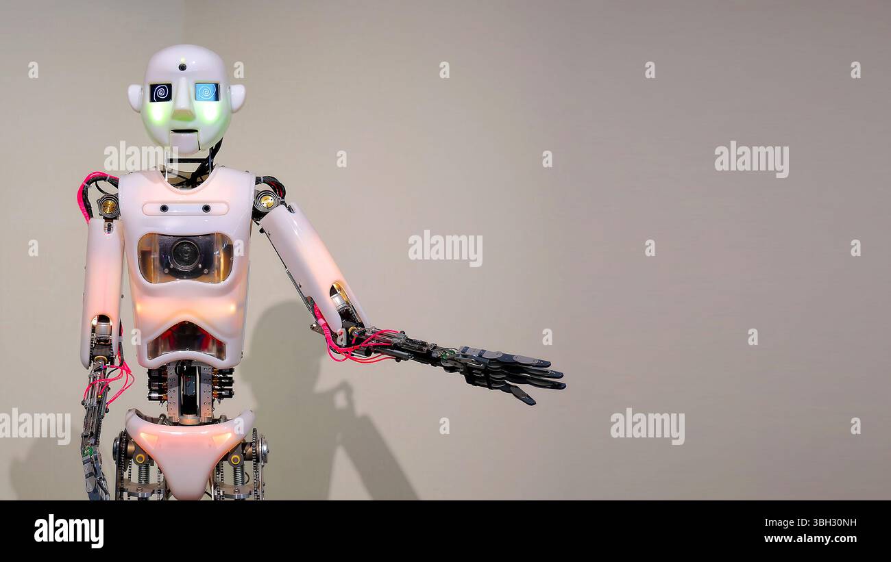Humanoider Roboter mit ausgestrecktem Arm in der modernen Ausstellung. Ein humanoider Roboter mit beleuchteten Gesichtszügen und einem verlängerten Arm steht gegen einen Stockfoto