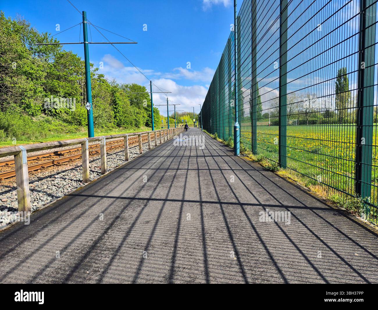 Weg mit Zaunschatten, der neben dem Eisenbahngleis in Nottingham, England verläuft Stockfoto