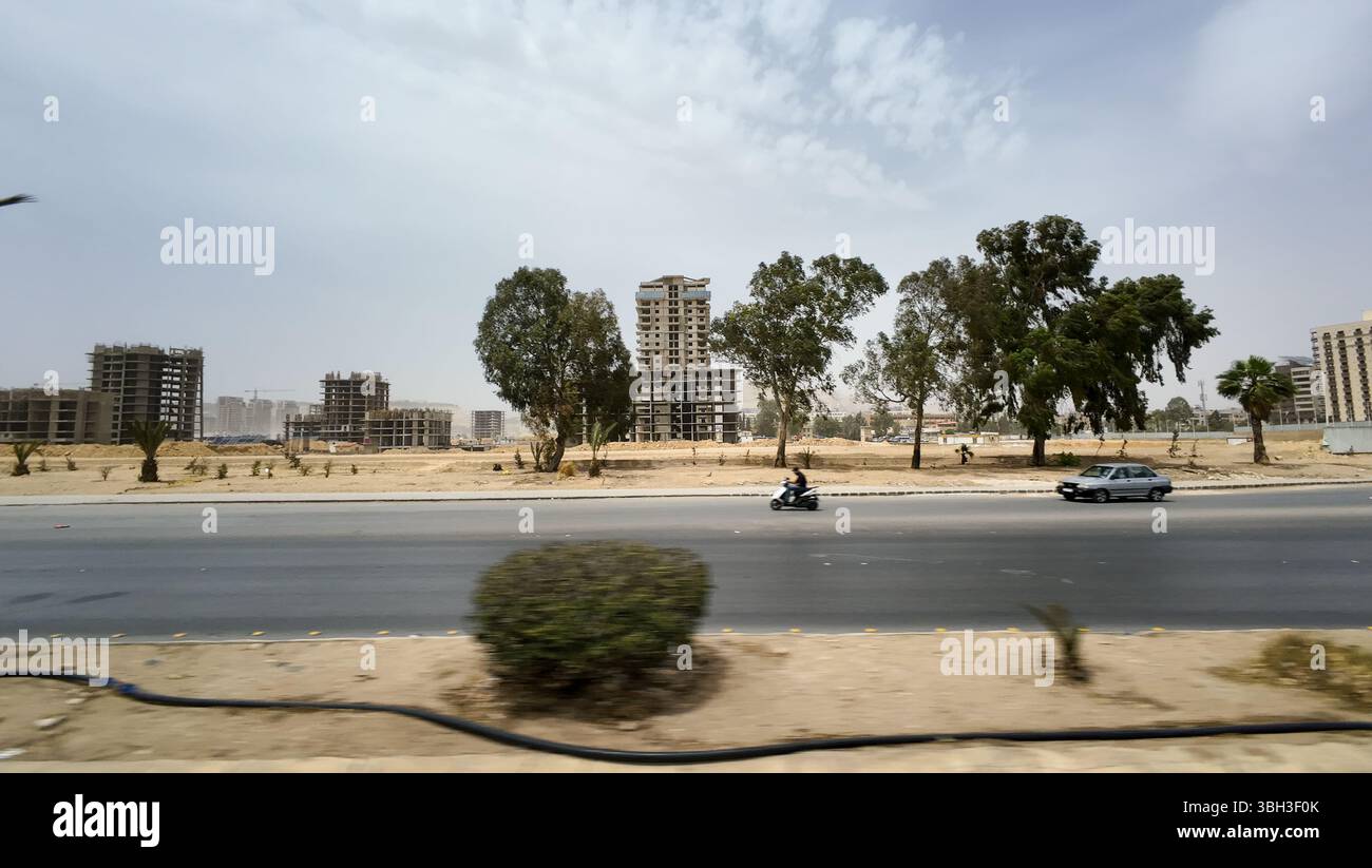 Ein zerstörtes Stadtbild mit bombardierten Gebäuden, Bäumen und einer Straße mit Fahrzeugen. In Damaskus Stockfoto