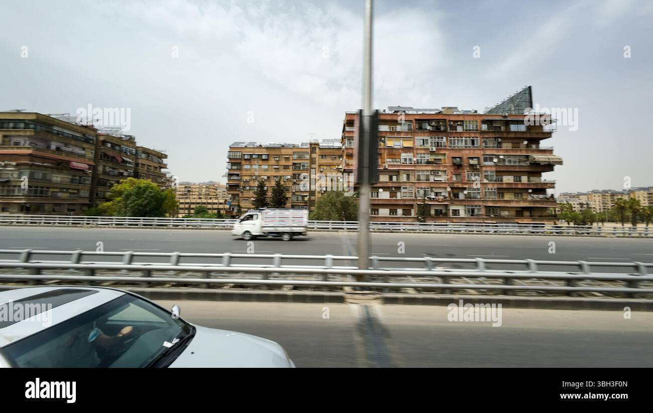 Ein Stadtbild mit Wohnhäusern und einem fahrenden Auto auf einer Autobahn. In Damaskus Stockfoto