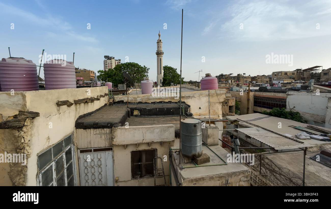 Blick von der Dachterrasse auf einen städtischen Bereich mit Wassertanks, Satellitenschüsseln und einem entfernten Moschee-Minarett unter klarem blauen Himmel. In der Altstadt von Damaskus Stockfoto