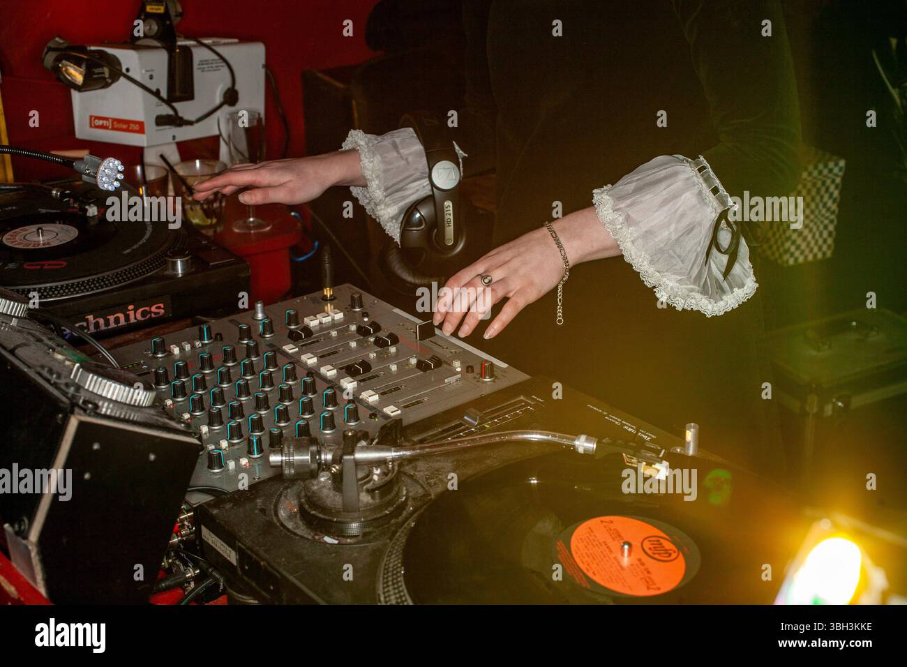 Eine DJ-Frau in der 1960er Jahre Vintage Mod-Mode spinnt Schallplatten bei einem Retro Club Night in London. Stockfoto