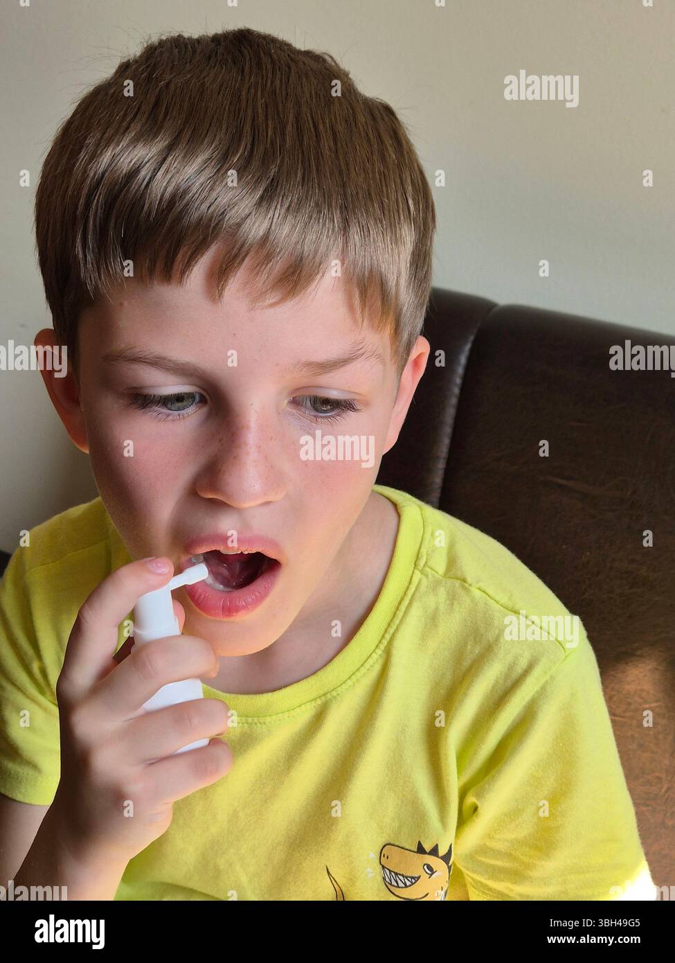 Das Kind hat Halsschmerzen. Der Junge sprüht ein Halsschmerzen-Heilmittel. Spray für Halsschmerzen in den Händen. Stockfoto