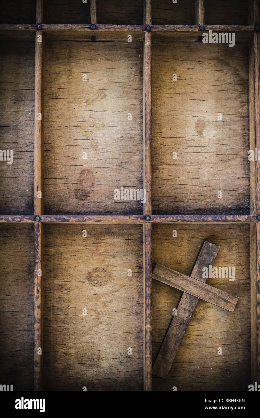 Ein Holzkreuz in einer Vintage-Buchdruckschublade aus Holz Stockfoto