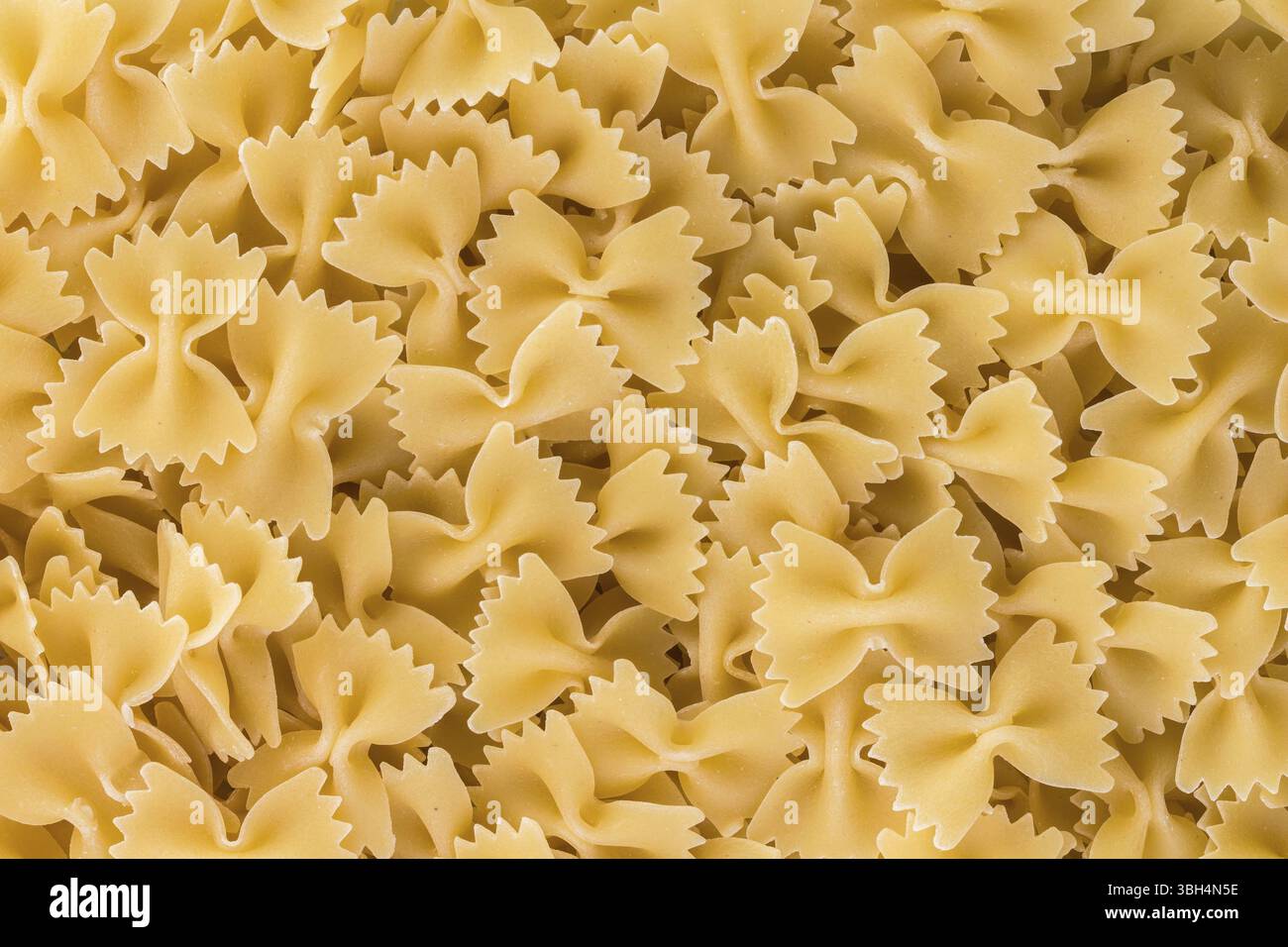 Ungekochte Pasta mit Fliege (Farfalle). Der Name dieser Nudelsorte leitet sich vom italienischen Wort farfalla (Schmetterling) ab. Stockfoto