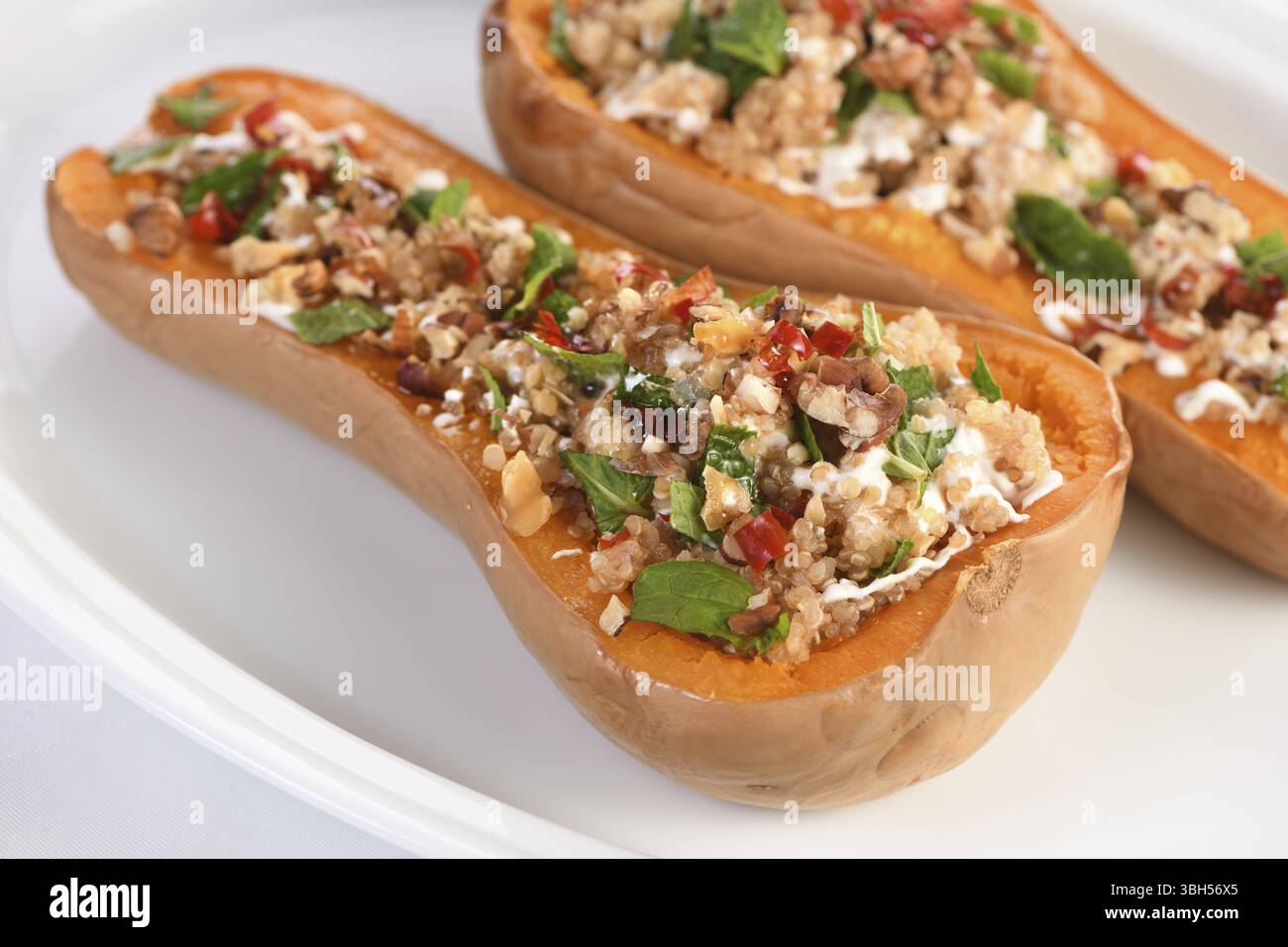Gebackener gefüllter Kürbis gefüllt mit Walnüssen, frischer Minze und Chili mit Quinoa Tabbouleh. Der Ahornsirup macht sie ausgezeichnet. Es ist eine gesunde Beilage Stockfoto